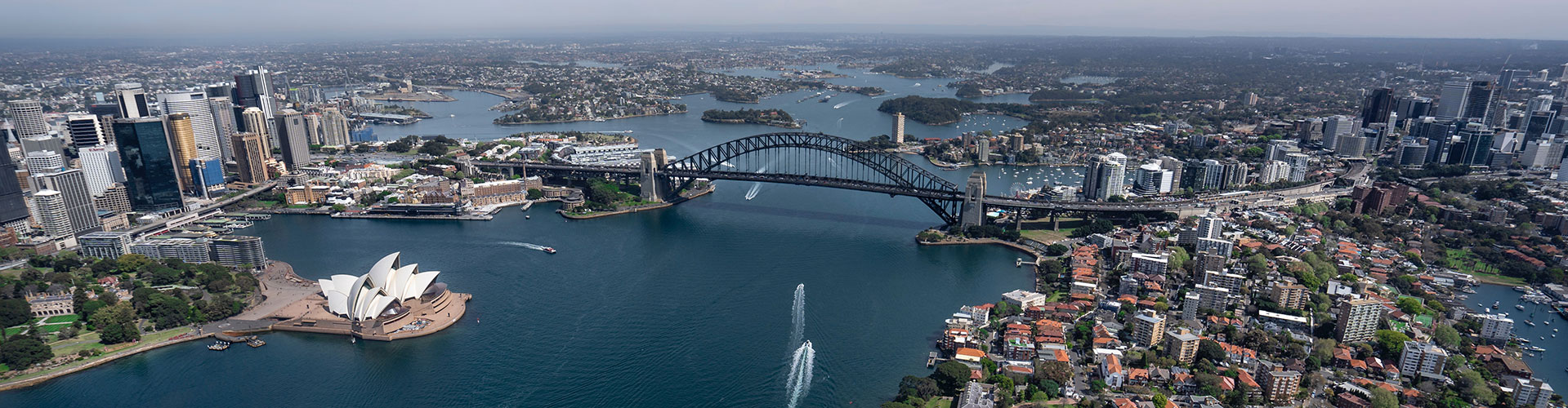 An aerial view of Sydney Harbor in Australia showing the city, Sydney Opera House and Sydney Harbor Bridge.