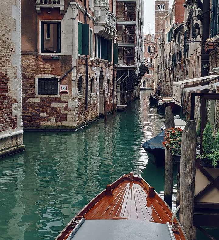 A luxury boat at a canal dock between buildings in Venice, Italy.
