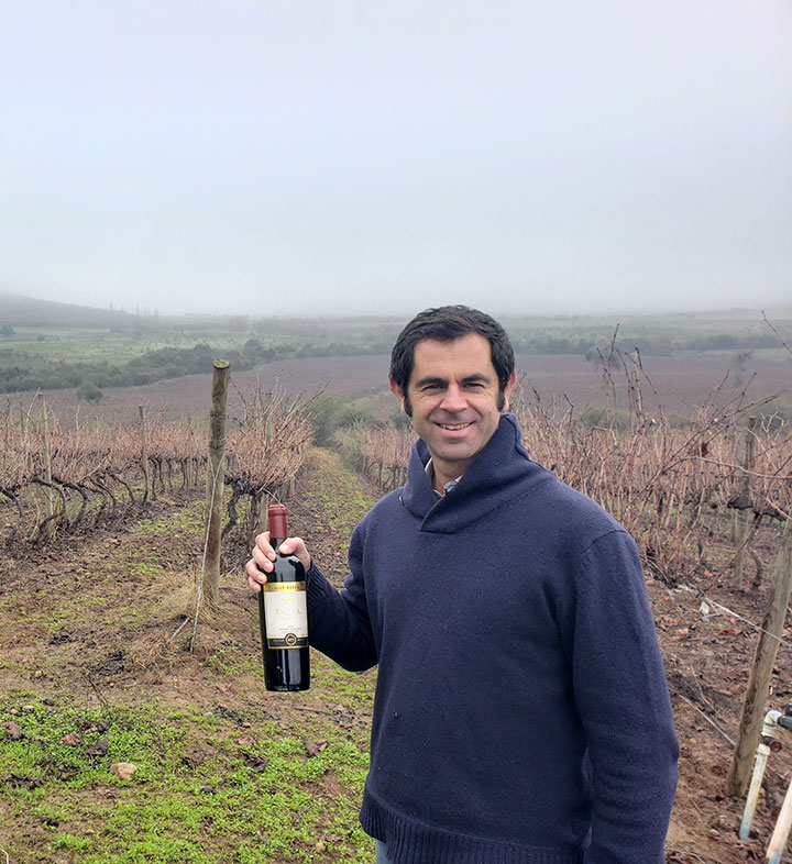 Bodegas Tagua Tagua owner, Santiago Correa, holding a bottle of wine in the Chilean vineyard.