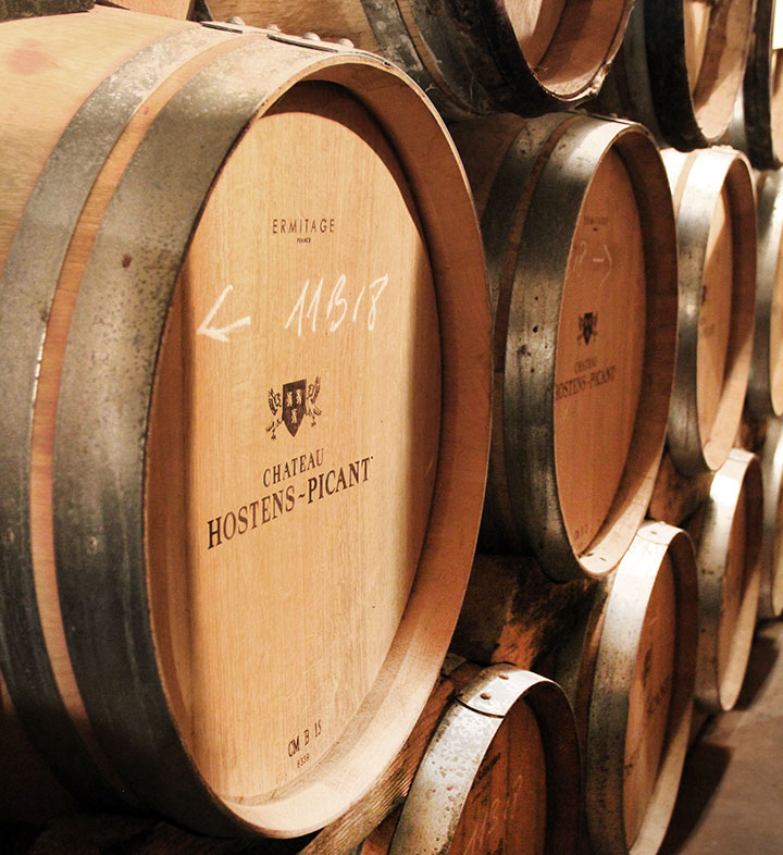 French oak wine barrels aging in the cellar of Chateau Hostens-Picant in Bordeaux, France.